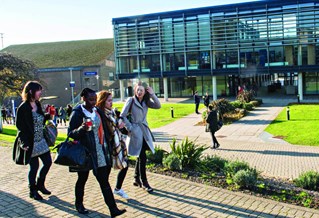 Students walking in front of Checkland Building at Falmer