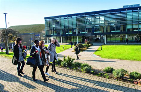 Students walking in front of the Checkland Building at Falmer