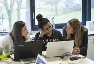 students working on a laptop with lecturer