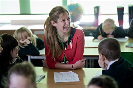 female trainee teacher in school setting smiling with pupils