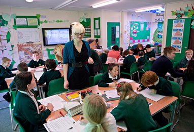Teacher in front of a table of children smiling