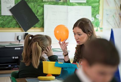 Primary school teacher with a ballon teaching children