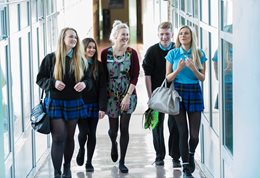 A group of secondary school pupils walking through a sunny corridor