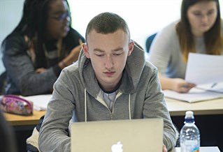 Male student working on laptop in classroom