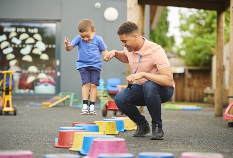 male teacher helping toddler on stepping blocks