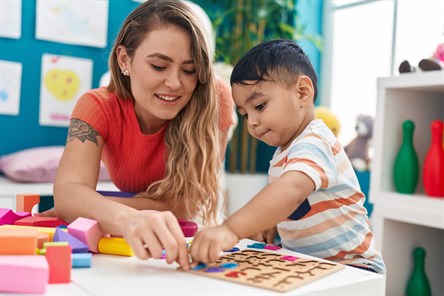 Female teacher and child playing with number puzzle