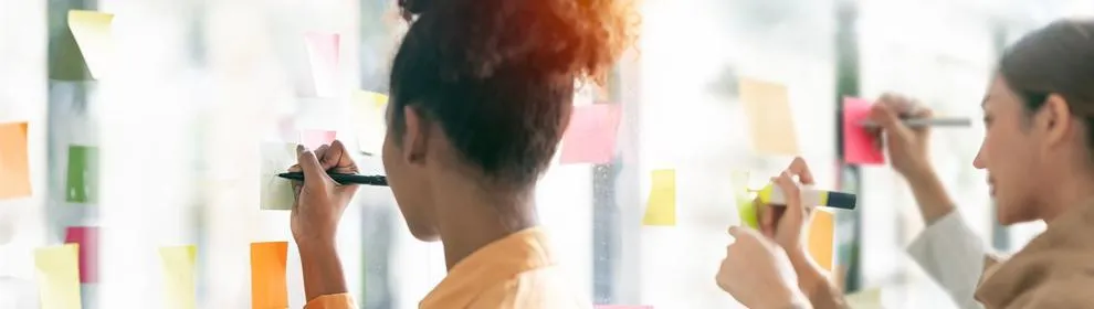 female student writing on post it note on wall