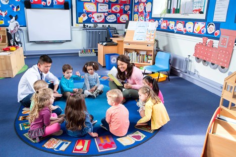 male and female teacher with group of toddlers in reception classroom