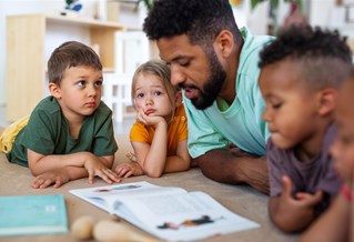 Student teacher reading a book to children