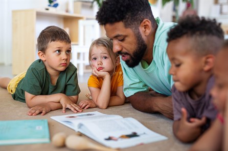 male teacher reading a book with children