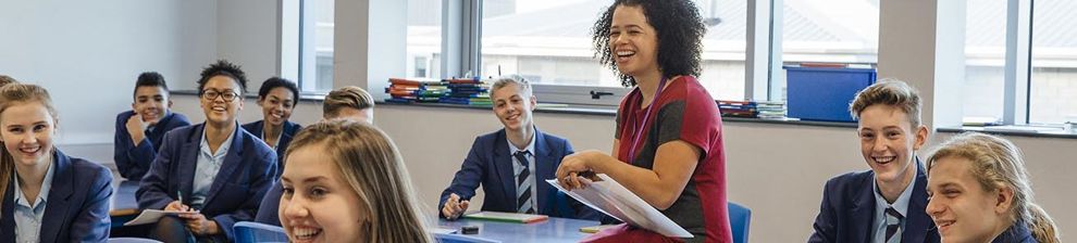 teacher sitting on desk with students