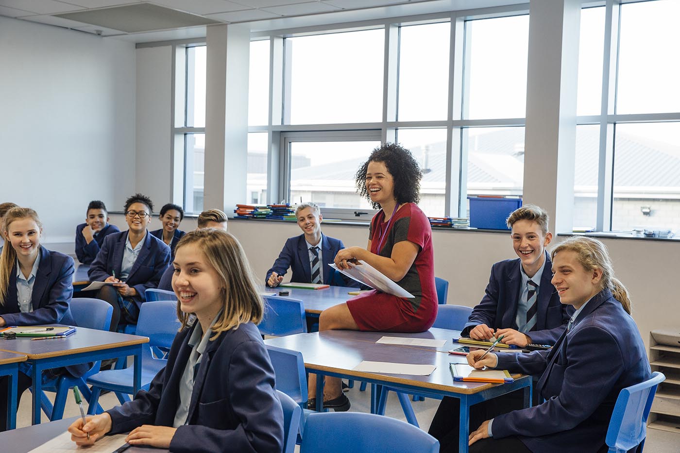 Teacher sitting on desk with students