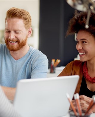 Two people laughing round a laptop