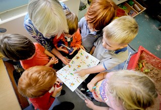 Teacher reading a book to a group of children at nursery