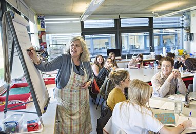 Primary school arts teacher drawing on a flipchart in front of the pupils