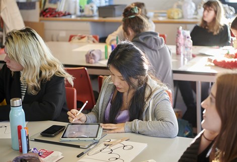 Art PGCE trainee teacher in a classroom, drawing on tablet