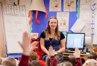 Teacher in front of infants with their hands up