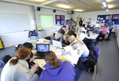 Students working in groups around tables with computers