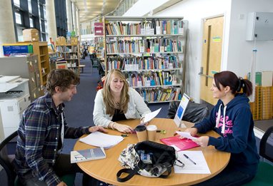 Three students around a table in the education library