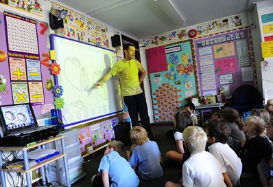 Student teacher at the front of a classroom of young pupils