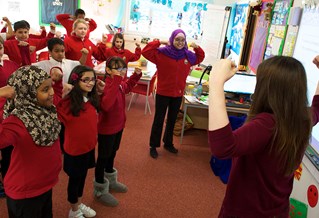 group of primary school children holding arms up