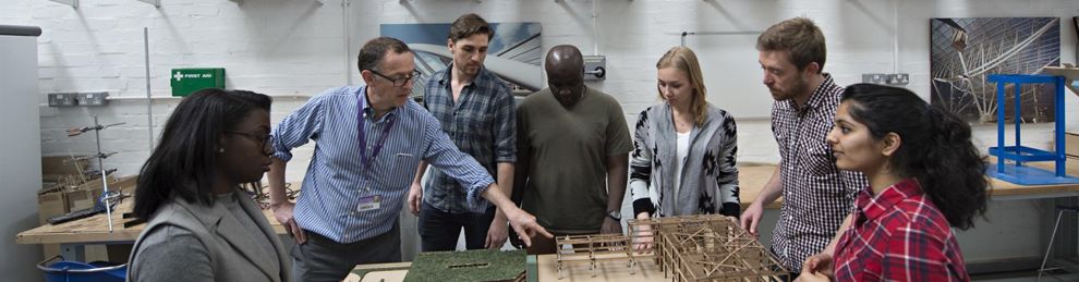 Students with lecturer standing around a model building
