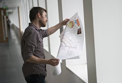 Architectural technology student looking at a technical drawing in the corridor