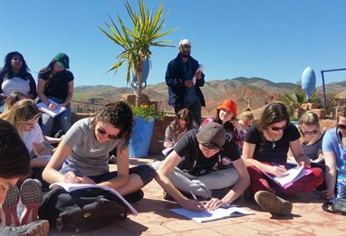 Students all sitting working outside with view of Atlas mountains behind them