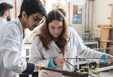 Two students in white coats working together