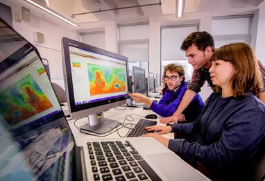 Three students using mapping software looking at computer screen