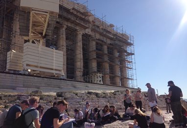 Students sitting at the base of an ancient ruin