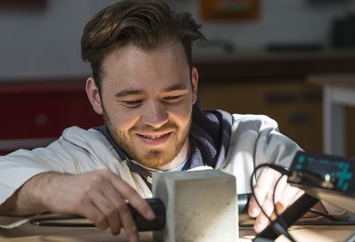 Close up of a smiling student measuring a concrete block