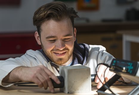 Close up of a person in a white lab coat testing a concrete block