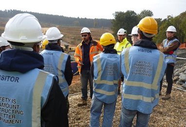 People in hard hats and hi-viz vests near a wood