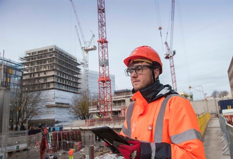 Student with a clipboard on a building site in high vis