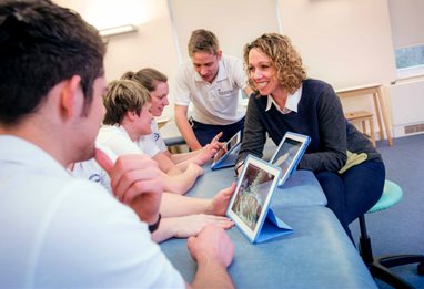 Physiotherapy students using tablets with lecturer