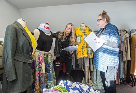 Two people arranging clothes on a mannequin