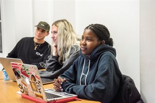 students - one white male, one white female, one Black female - in a tutorial with laptops