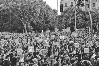 black and white picture of a protest march with people carrying placards saying NO