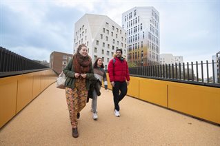 Three students walk across the pedestrian bridge, Moulsecoomb campus