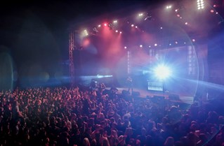 A concert with a large crowd and bright coloured lights