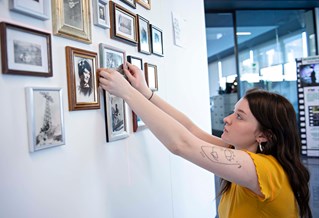 Student exhibiting framed photographs on a wall