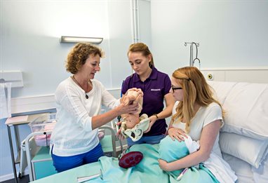 Midwifery students working with a model baby