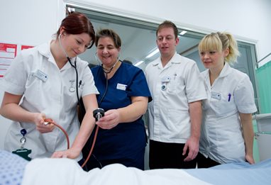 Four medical staff standing around a bed
