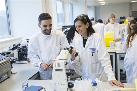 student and academic wearing white coats in a lab