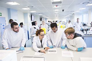 Four people in white lab coats having a discussion