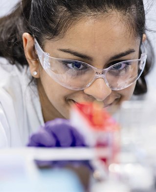 Female biomedical pharmaceutical researcher with protective eyewear and protective gloves