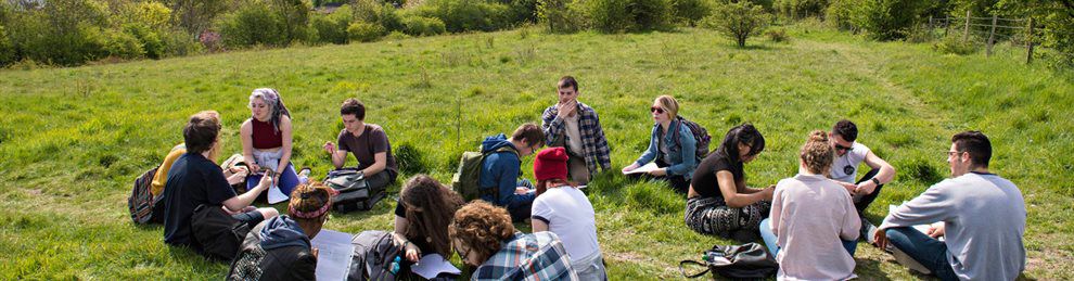 Students sitting in a woodland clearing on an ecology field trip