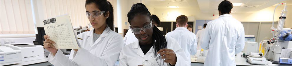 Students in white coats in a pharmacy lab