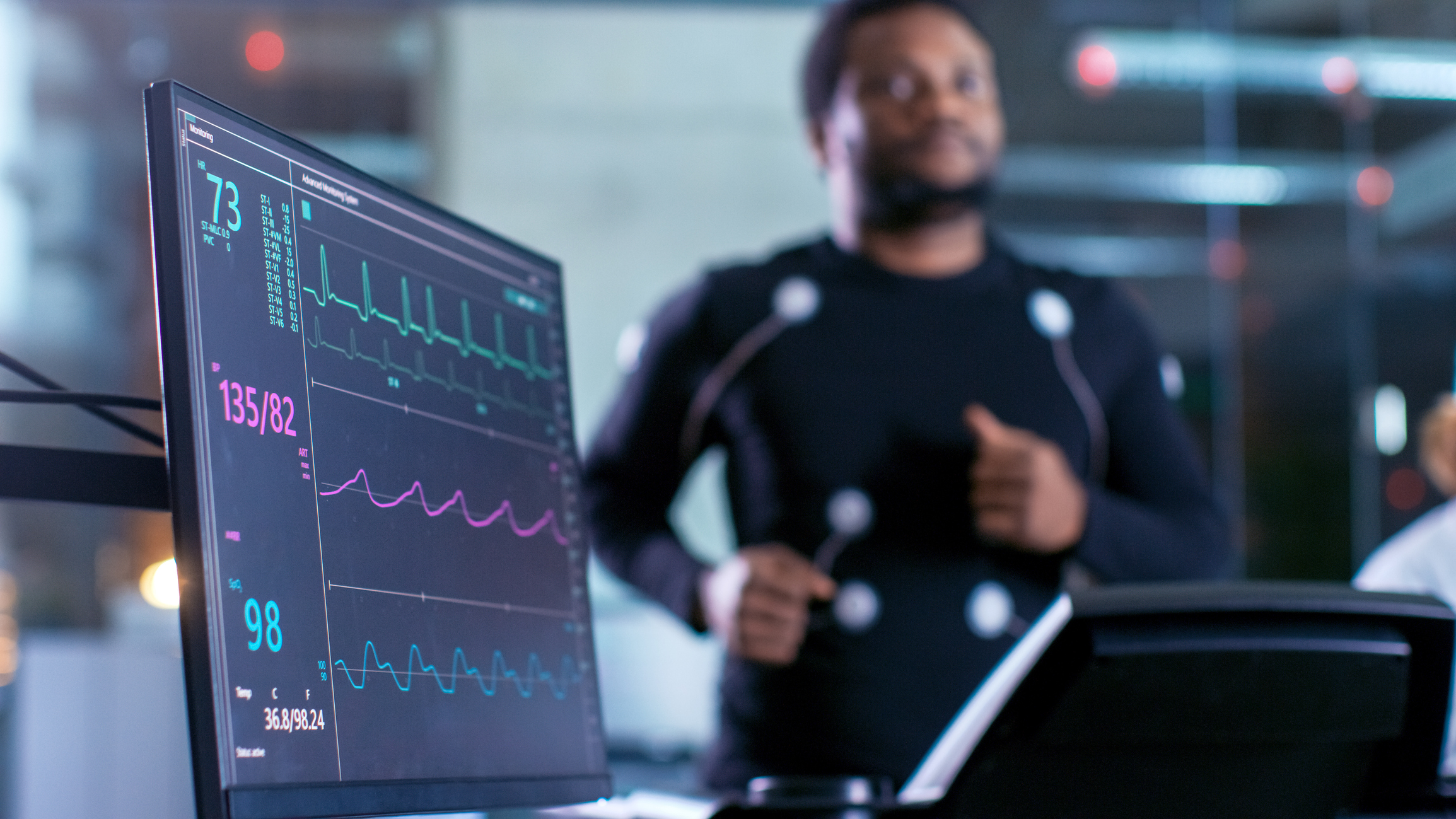 Athlete wearing high tech clothing with sensors on treadmill with computer display of heart rate